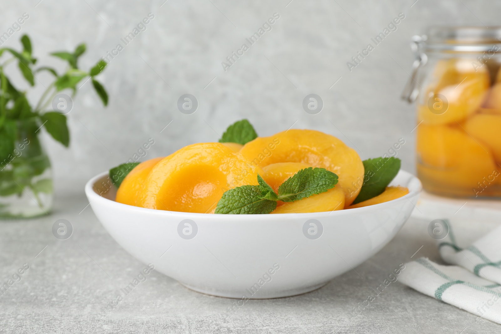 Photo of Canned peach halves in bowl on light table