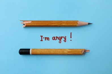 Photo of Broken pencil and inscription I'm Angry! on light blue background, flat lay