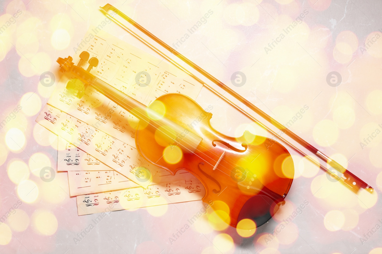 Image of Christmas and New Year music. Violin and music sheets on light background, bokeh effect