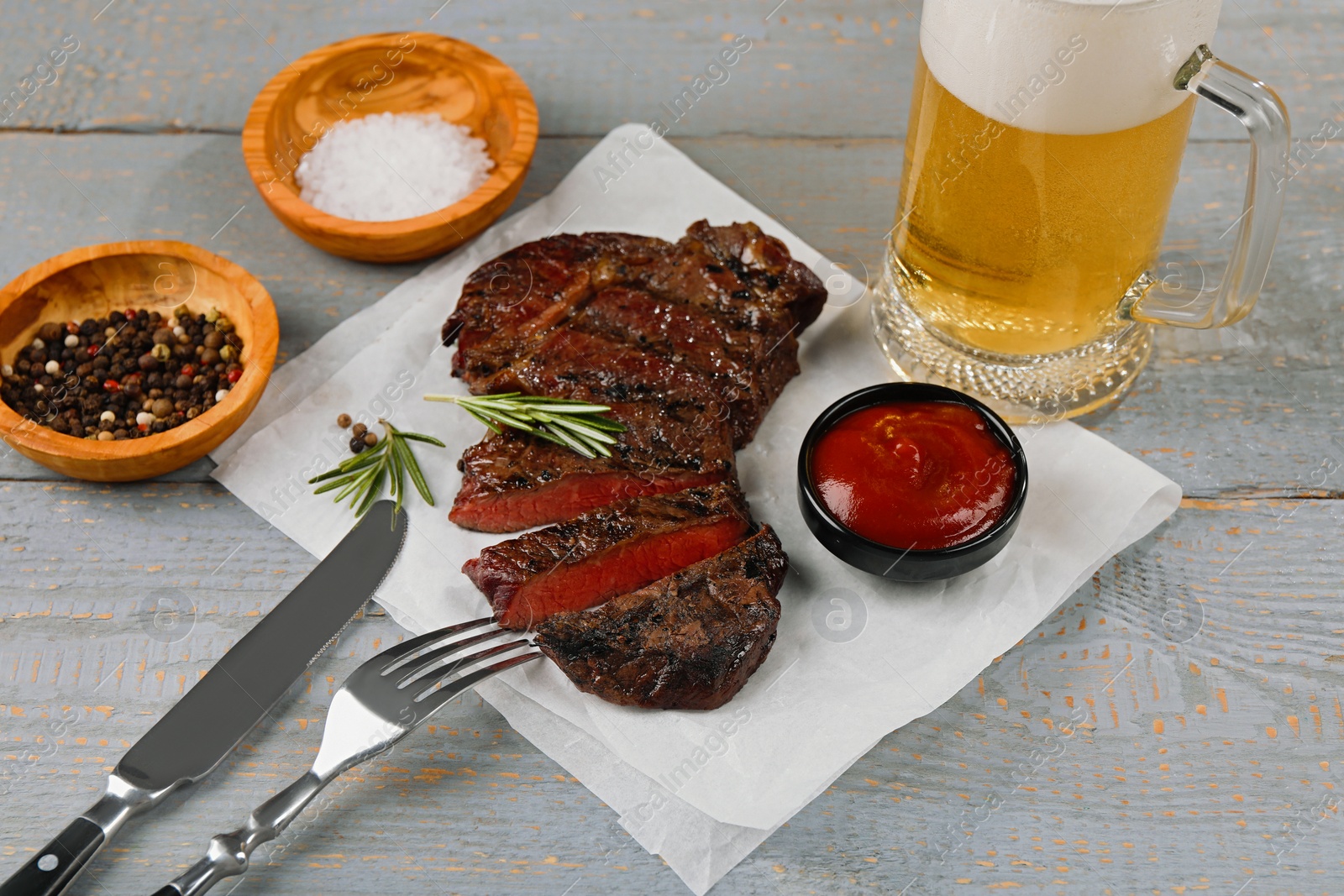 Photo of Mug with beer, fried steak and sauce on grey wooden table