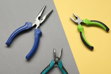 Different pliers on color background, flat lay