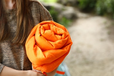 Photo of Woman holding rolled sleeping bag outdoors, closeup. Space for text