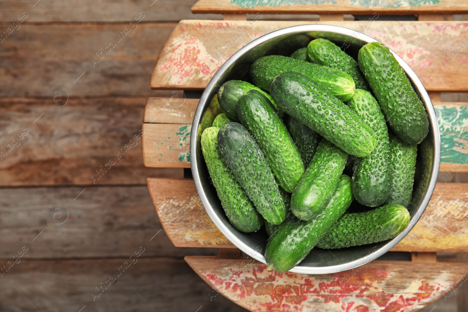 Photo of Bowl with ripe fresh cucumbers on table, top view