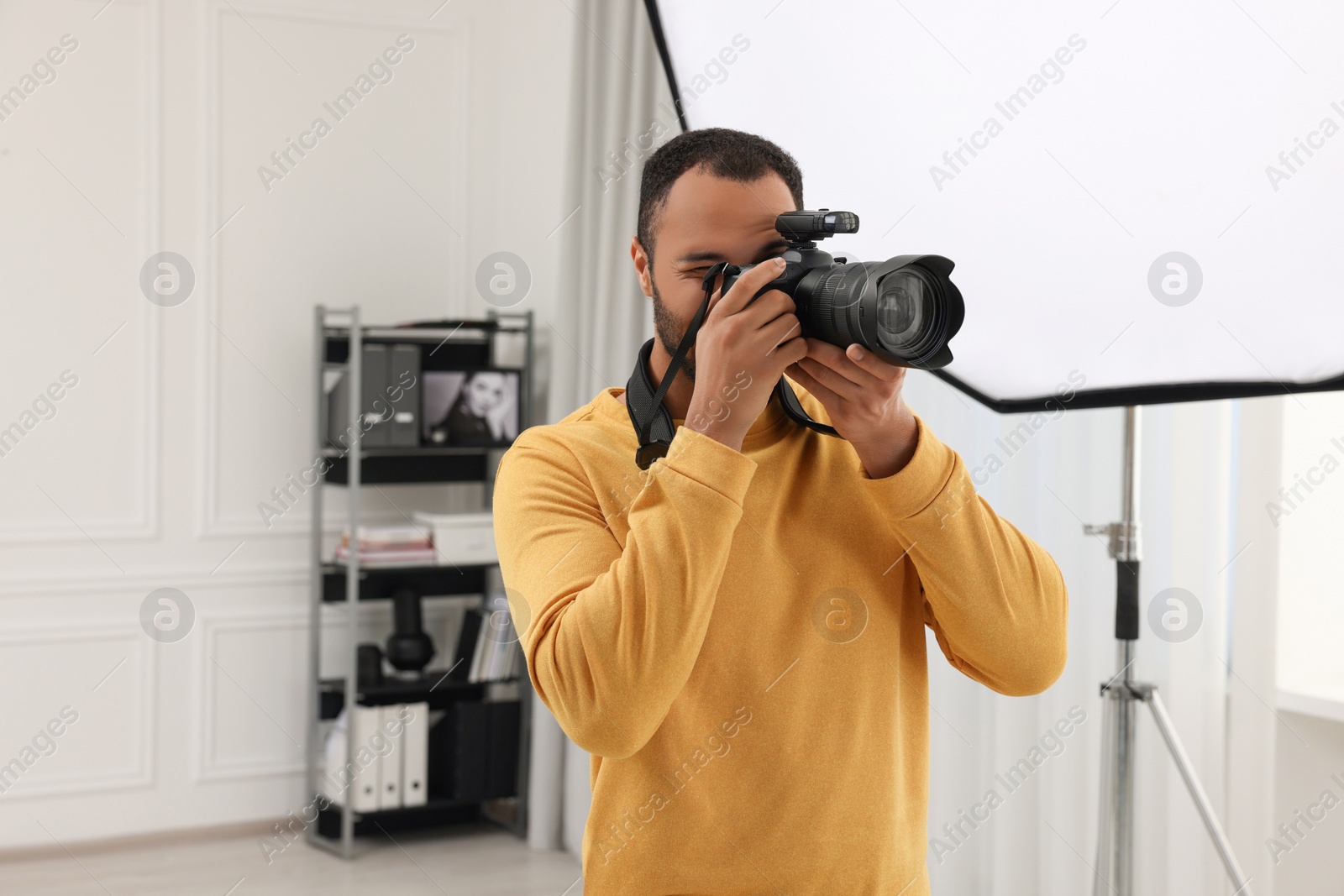 Photo of Young professional photographer taking picture in modern photo studio