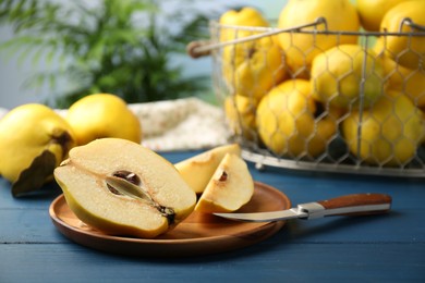 Photo of Tasty ripe quince fruits and knife on blue wooden table, closeup