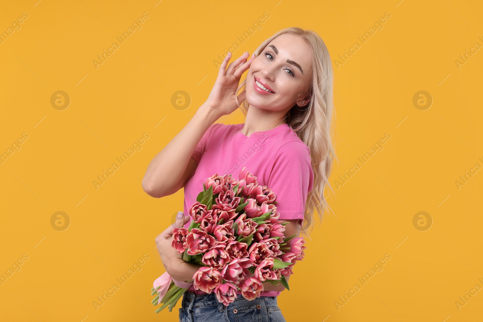 Photo of Happy young woman with beautiful bouquet on orange background