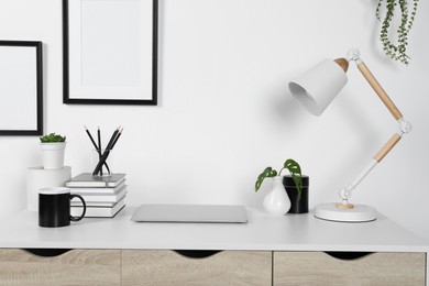 Photo of Home workplace. Laptop, lamp and stationery on white wooden desk