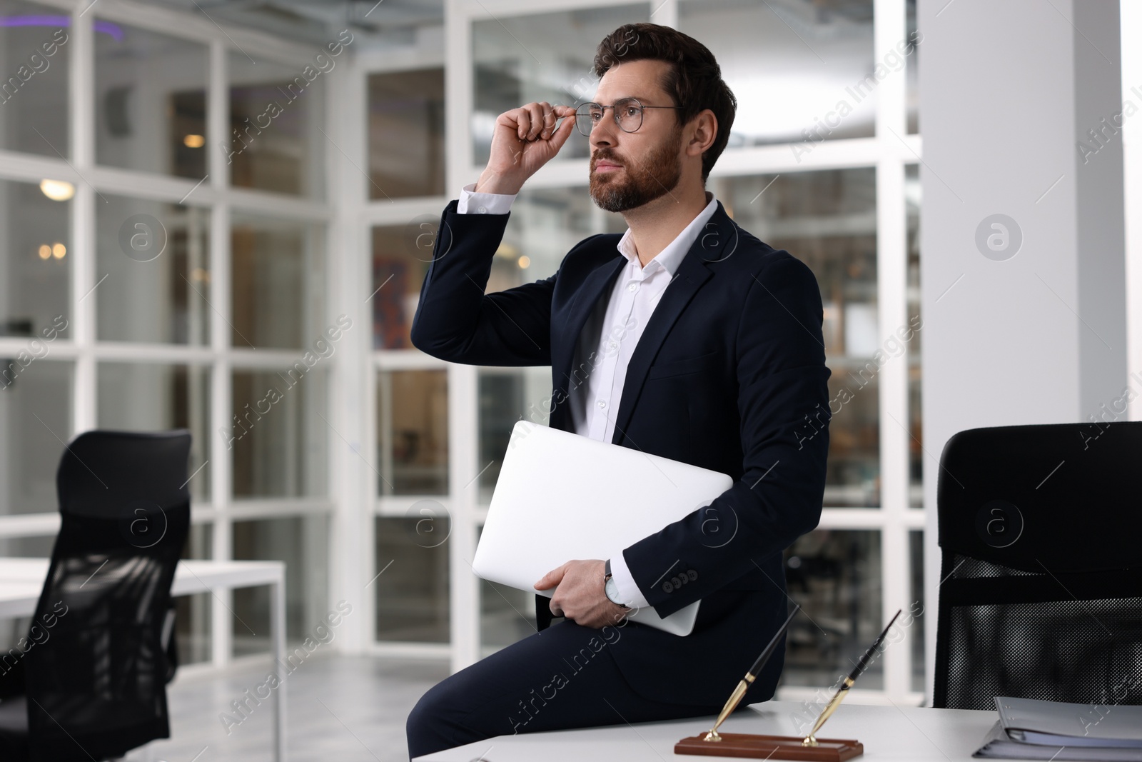 Photo of Portrait of handsome man with laptop in office. Lawyer, businessman, accountant or manager