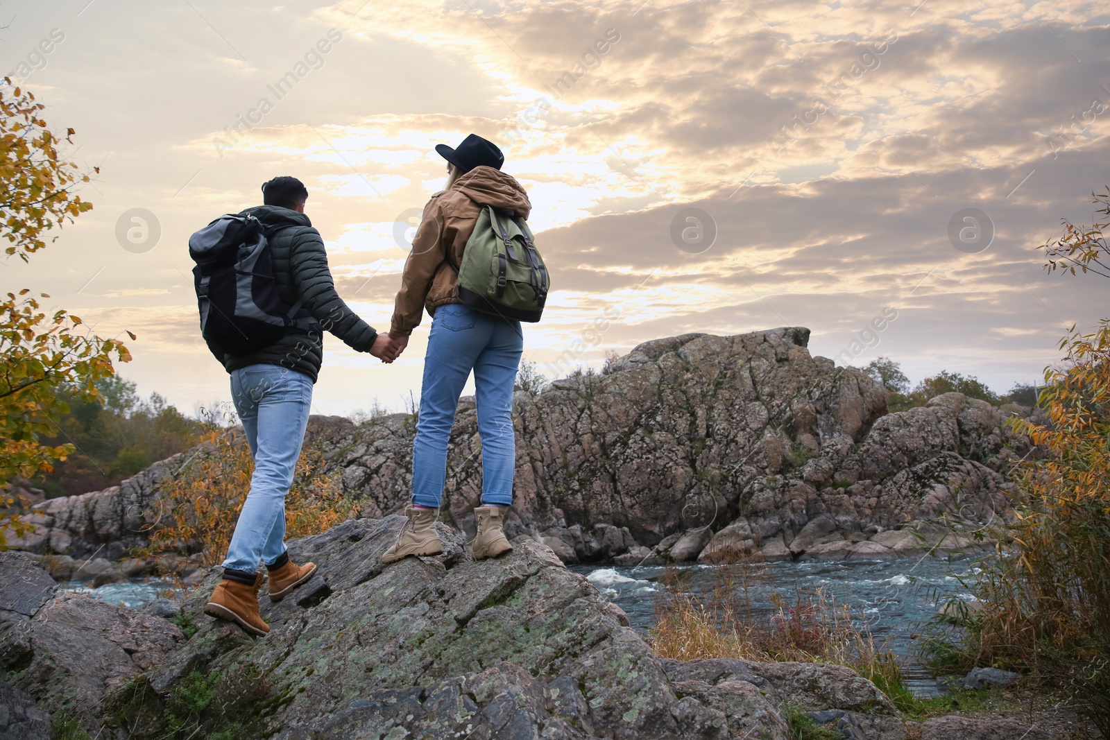 Photo of Couple of hikers enjoying beautiful view near mountain river, back view