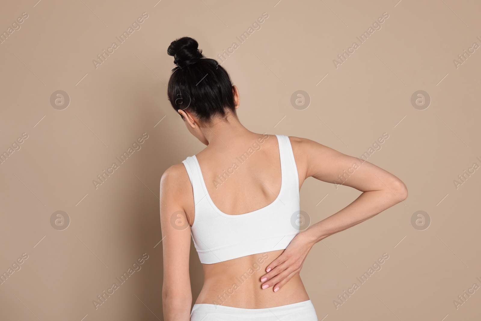 Photo of Woman suffering from pain in back on beige background