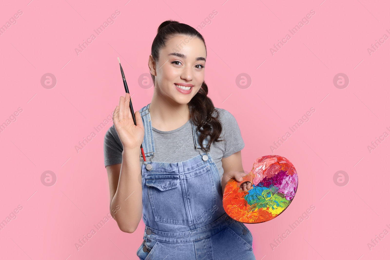 Photo of Woman with painting tools on pink background. Young artist