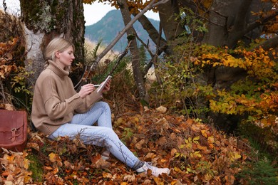 Photo of Young woman drawing on tablet outdoors, space for text