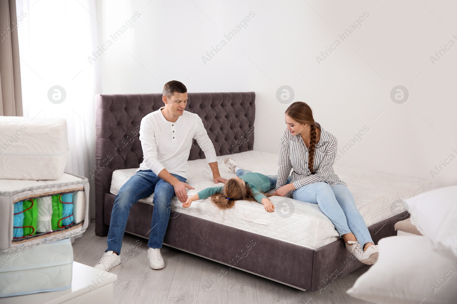 Photo of Happy family choosing mattress in furniture store