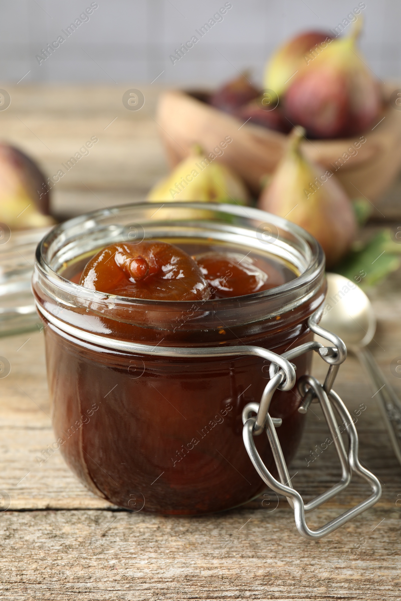 Photo of Jar of tasty sweet fig jam on wooden table