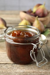 Jar of tasty sweet fig jam on wooden table