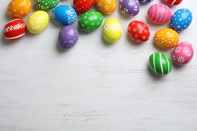 Decorated Easter eggs and space for text on wooden background, top view