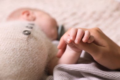 Mother and her newborn baby on light grey knitted plaid, closeup