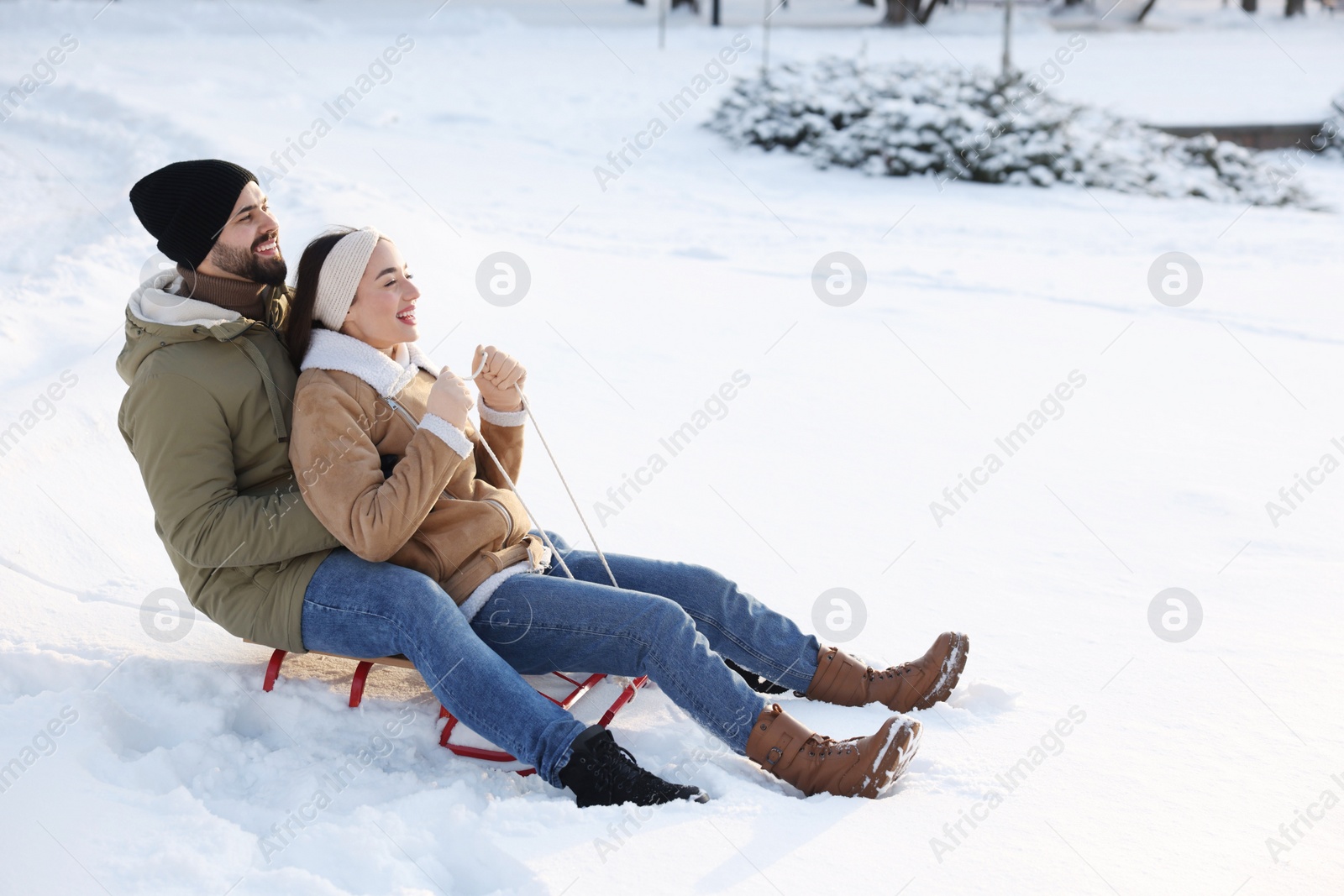 Photo of Happy young couple sledding outdoors on winter day