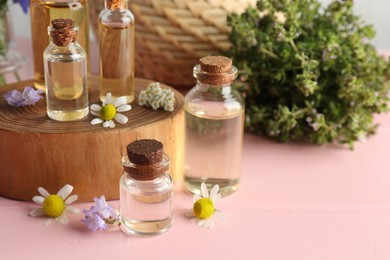 Photo of Aromatherapy. Different essential oils and flowers on pink wooden table