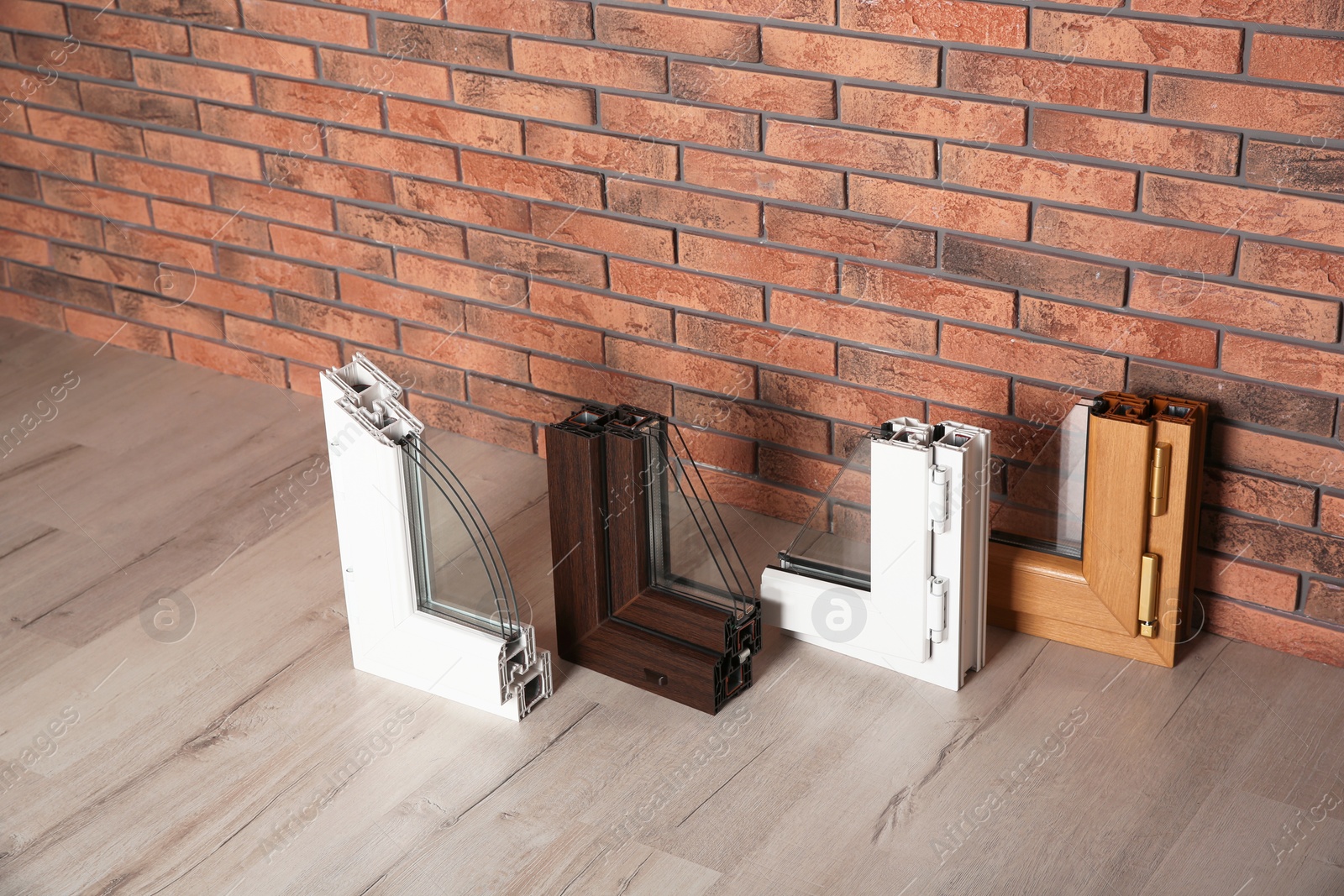 Photo of Samples of modern window profiles on floor against brick wall. Installation service