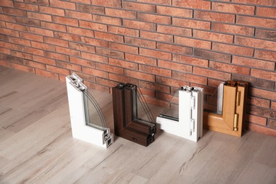 Photo of Samples of modern window profiles on floor against brick wall. Installation service