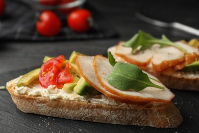 Photo of Slate plate of delicious chicken bruschettas on table, closeup