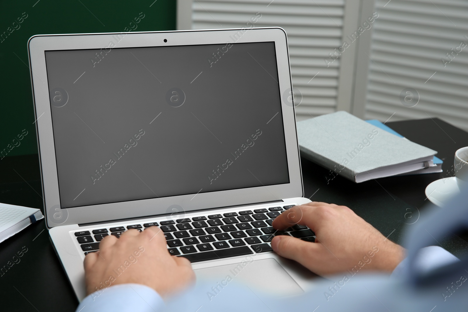 Photo of Young man using modern laptop at table, closeup