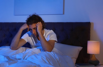 Handsome young man suffering from insomnia in dark room at night. Bedtime