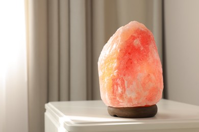 Himalayan salt lamp on white table indoors, space for text