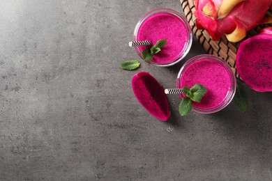 Photo of Delicious pitahaya smoothie, fruits and fresh mint on grey table, flat lay. Space for text
