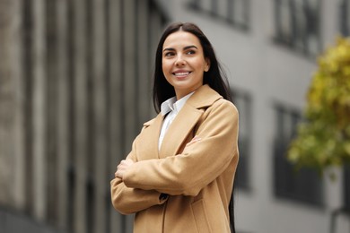 Photo of Smiling woman with crossed arms outdoors. Lawyer, businesswoman, accountant or manager