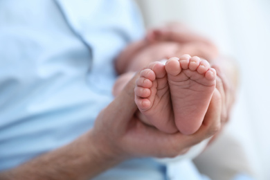 Photo of Father holding his newborn baby at home, closeup. Space for text