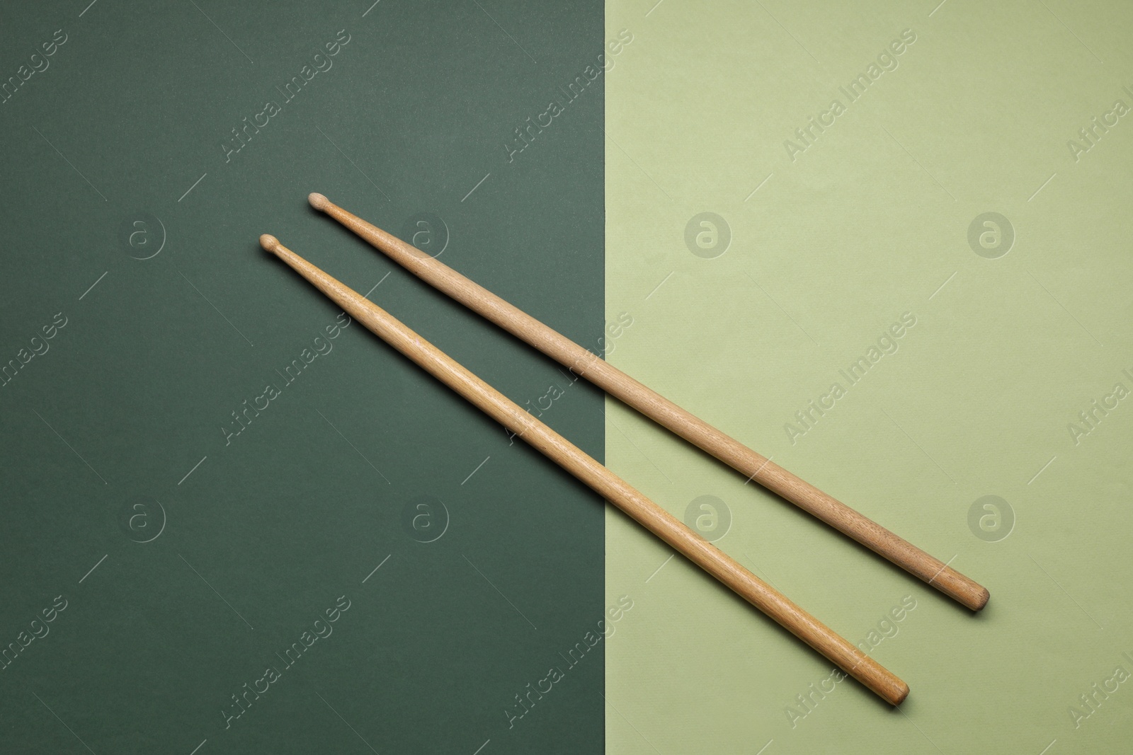 Photo of Two wooden drum sticks on color background, top view