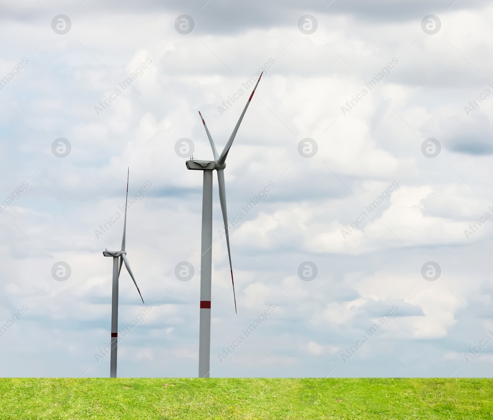 Image of Alternative energy source. Wind turbines in field under cloudy sky