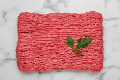 Photo of Raw fresh minced meat with parsley on white marble table, top view