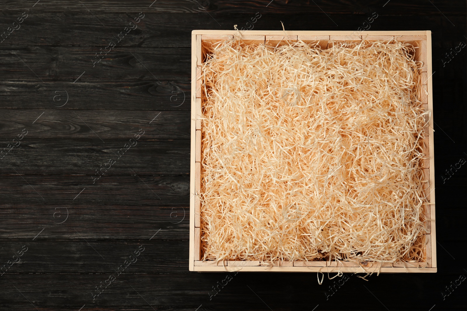 Photo of Wooden crate with filler on dark background, top view. Space for text