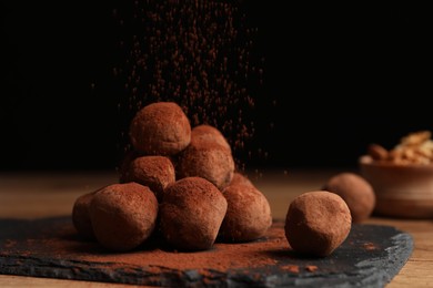 Photo of Tasty chocolate truffles powdered with cacao on slate board