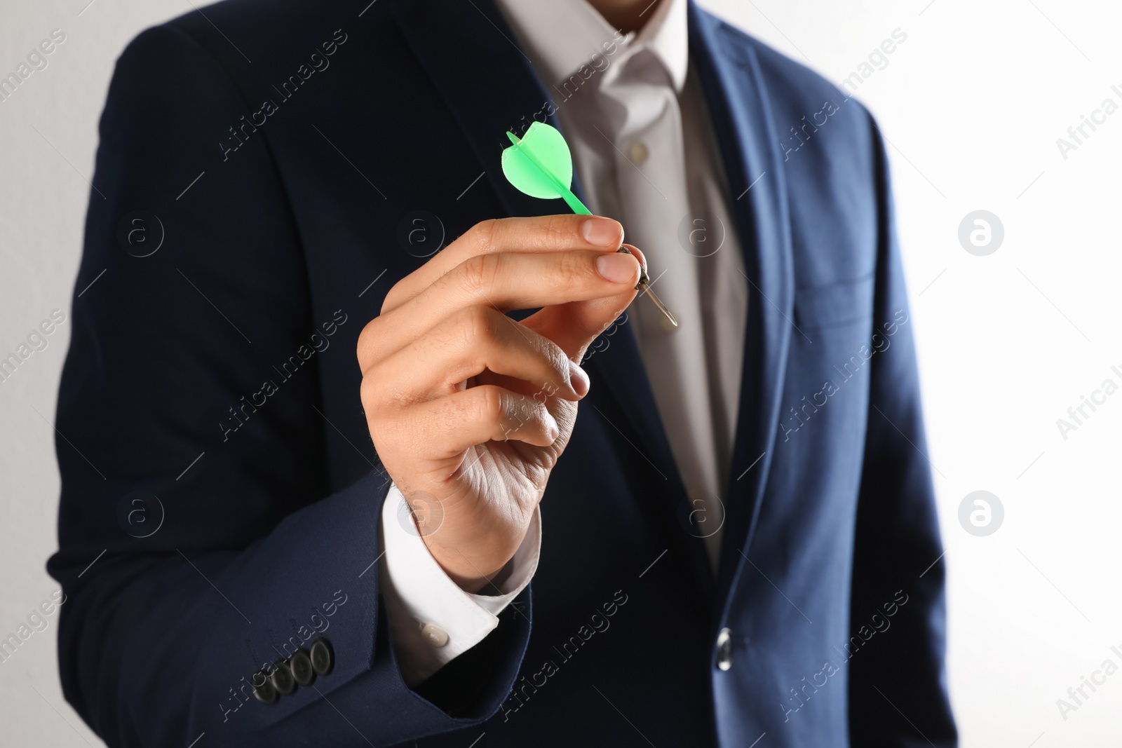 Photo of Man holding green dart on light background, closeup