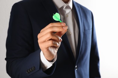 Photo of Man holding green dart on light background, closeup