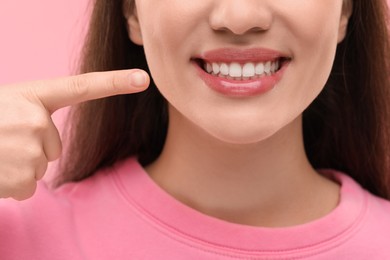 Photo of Beautiful woman showing her clean teeth and smiling on pink background, closeup