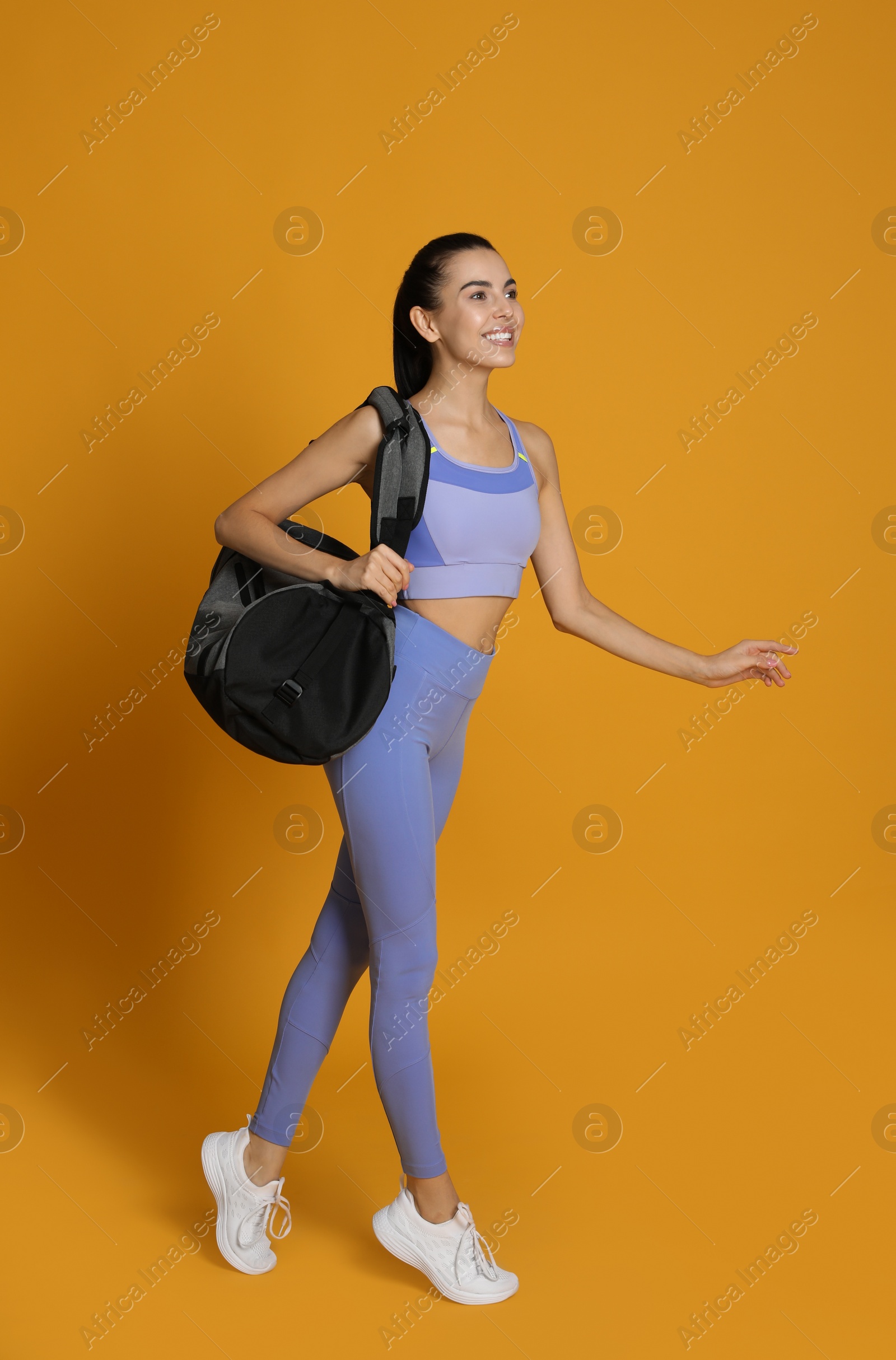 Photo of Beautiful woman with sports bag on yellow  background