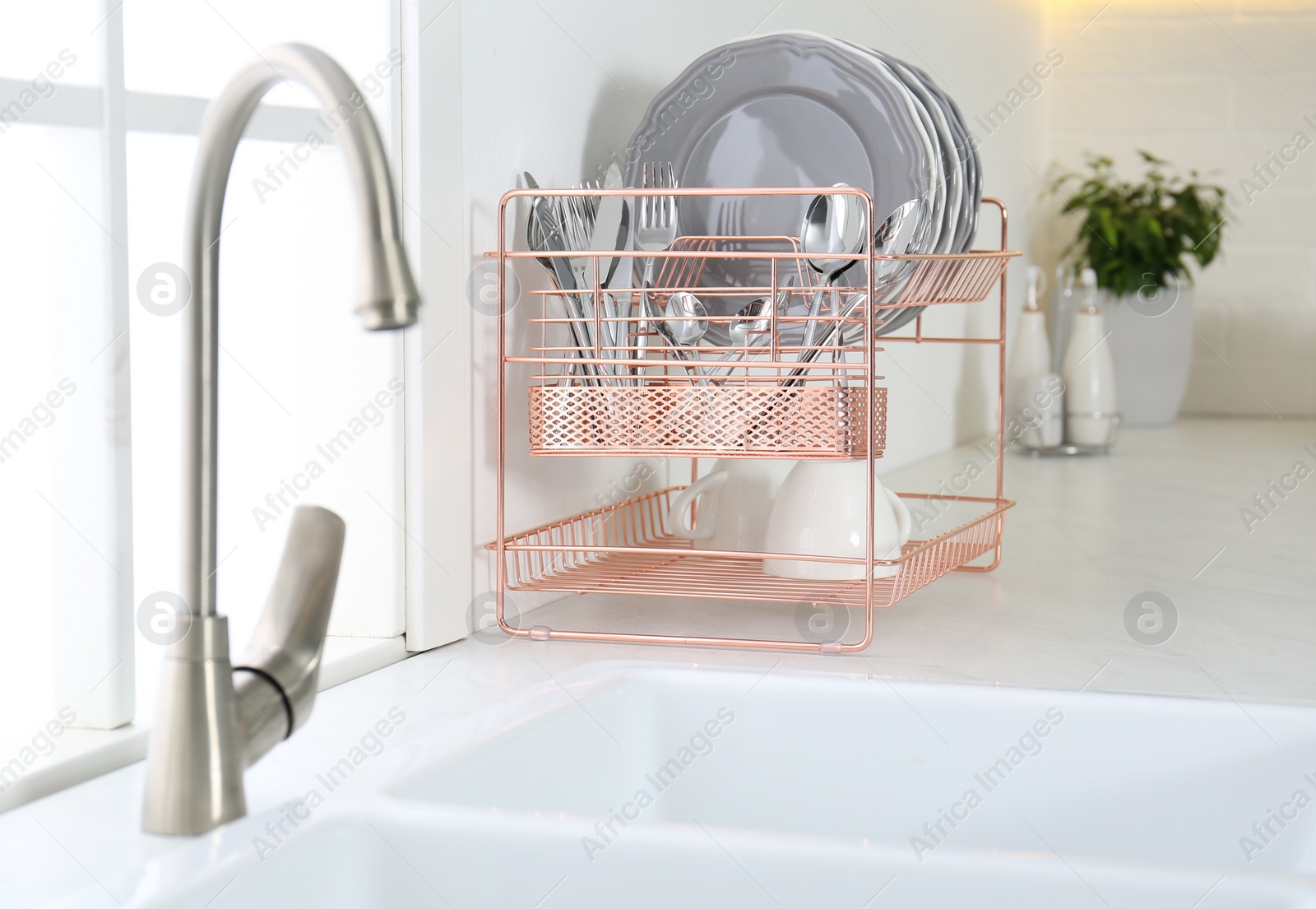 Photo of Clean dishes on drying rack in modern kitchen interior