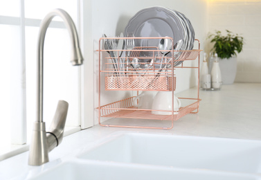 Clean dishes on drying rack in modern kitchen interior