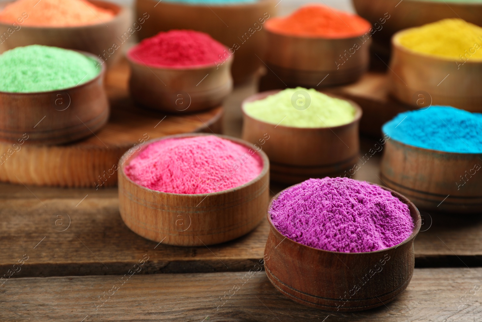 Photo of Colorful powder dyes on wooden background, closeup. Holi festival