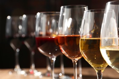 Photo of Different tasty wines in glasses against blurred background, closeup