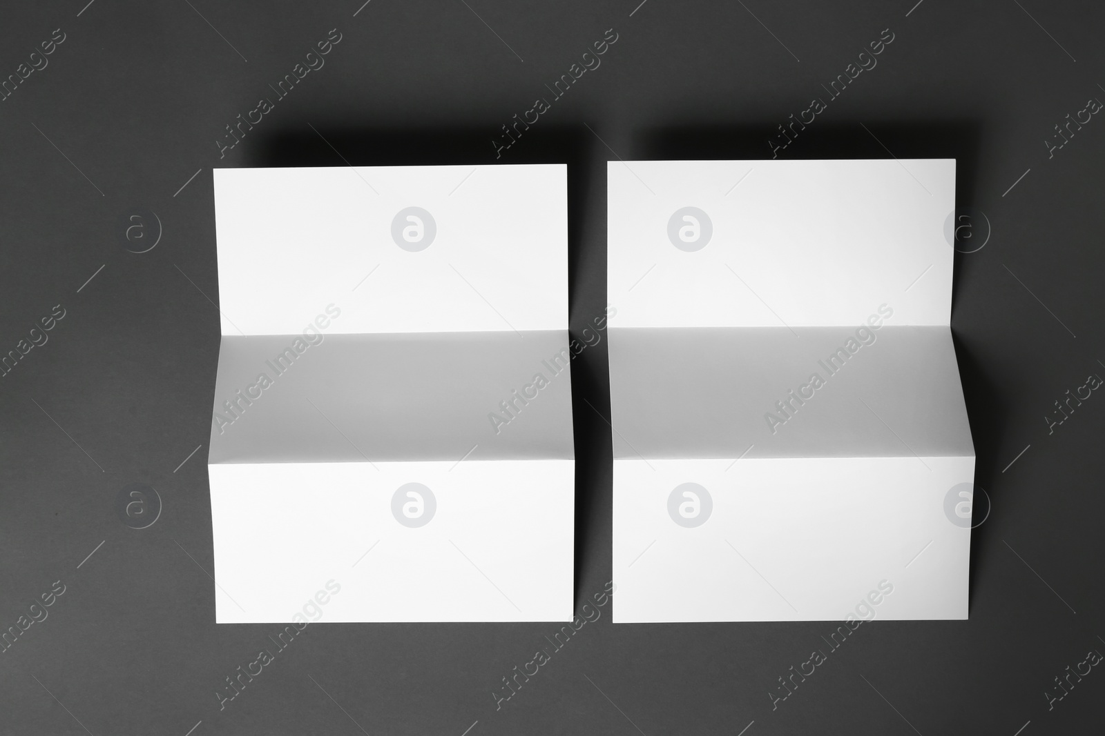 Photo of Two blank brochures on dark grey background, flat lay. Mock up for design