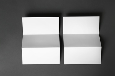 Photo of Two blank brochures on dark grey background, flat lay. Mock up for design