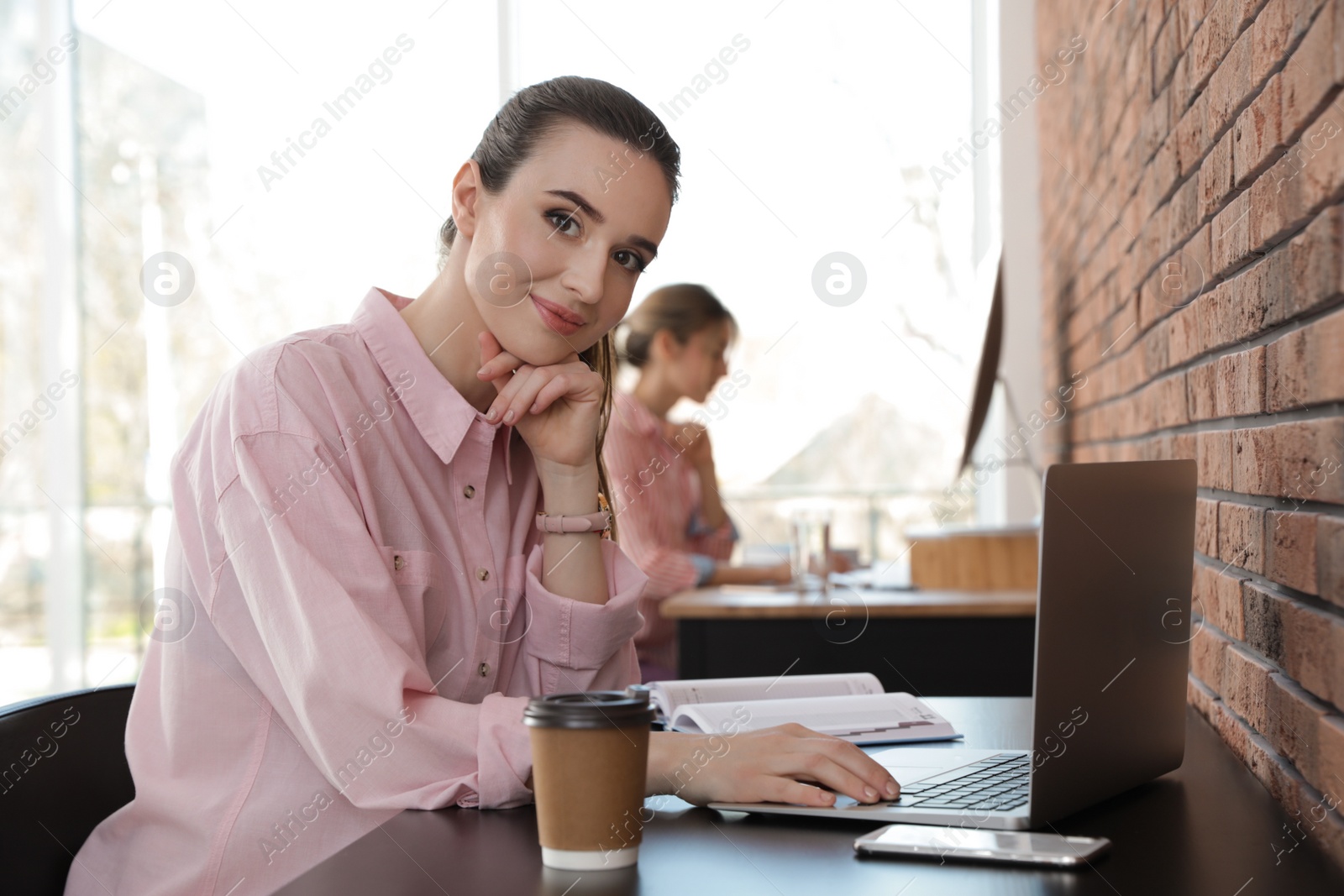 Photo of Young businesswoman using laptop at table in office