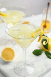 Photo of Delicious bee's knees cocktail with ice and lemon twist on white table