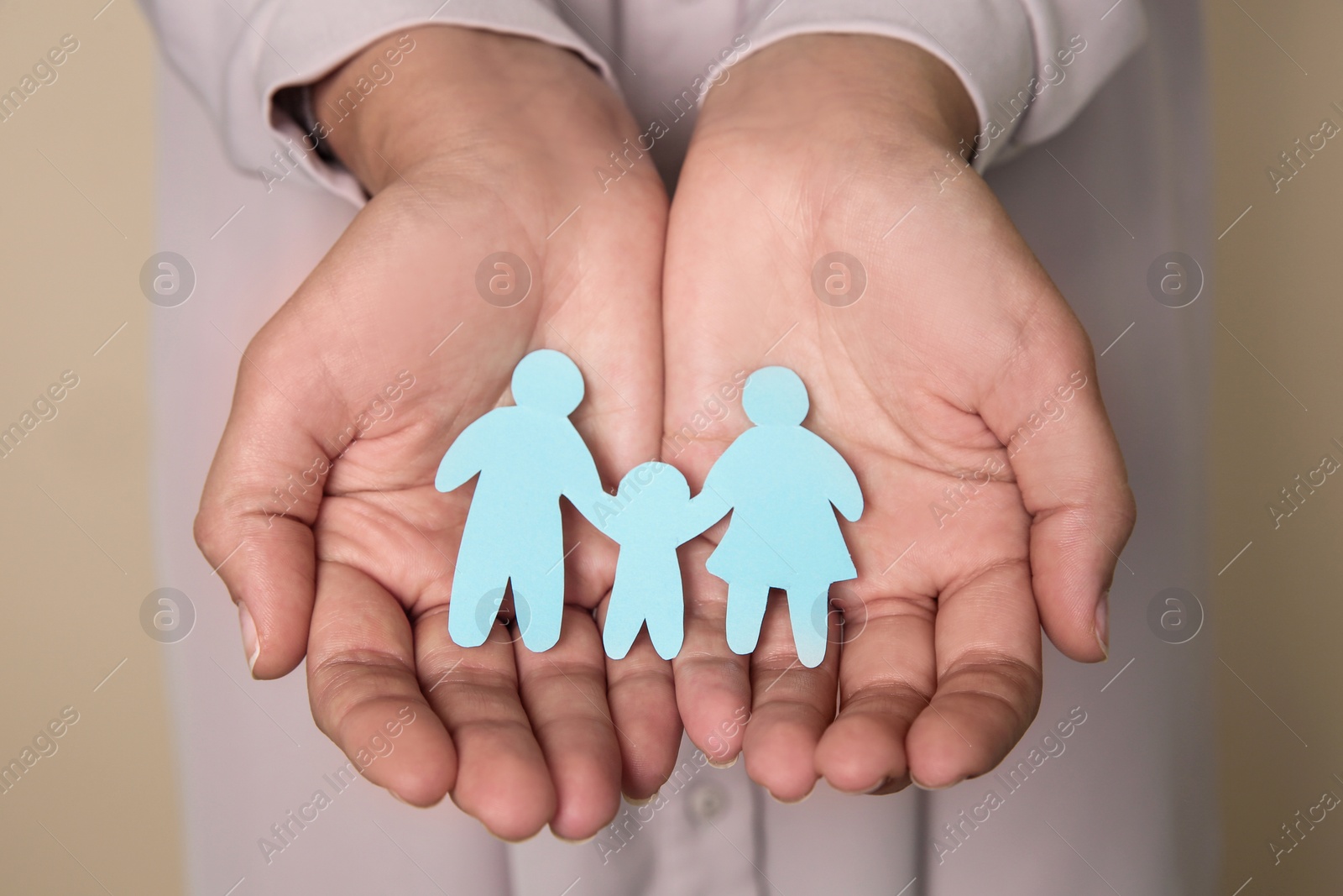 Photo of Young woman holding paper family cutout on color background, closeup